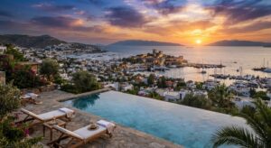 الوصف: A luxury infinity pool overlooking the turquoise Aegean Sea, whitewashed houses, and Bodrum Castle at sunset.