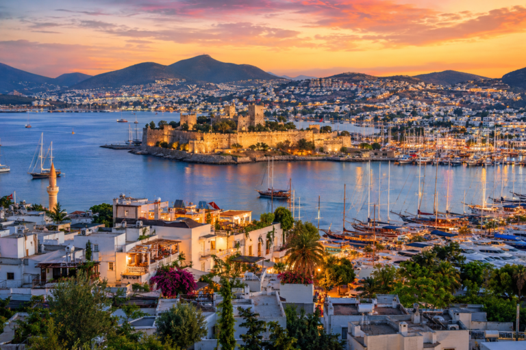 "Aerial view of Bodrum Town marina, castle, and white houses during sunset - Best areas to stay in Bodrum Turkey"